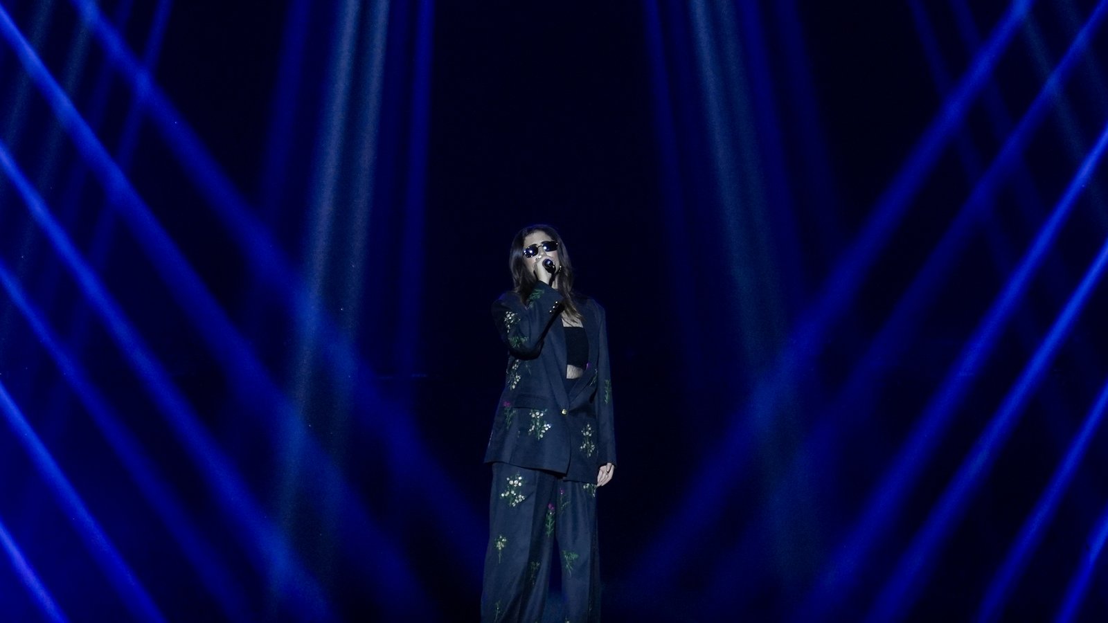 Singer on stage under crossing blue beams