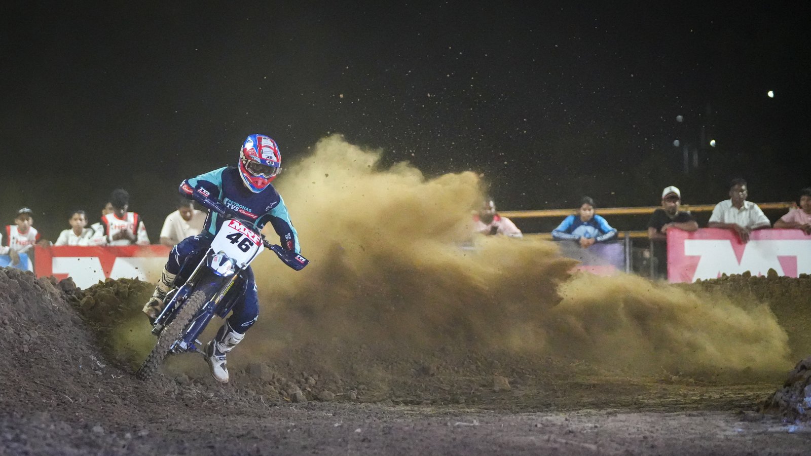 Motocross rider carving through dirt, night race
